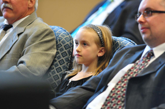 Eight-year-old Haley Morphy – an auction company CEO in training – listens intently as her father, Dan Morphy, speaks to the group that gathered in the new saleroom. At left is architect Eldon Stoltzfus; at right is Matt Mack, engineering manager of Ludgate Engineering Corp. Morphy Auctions image.